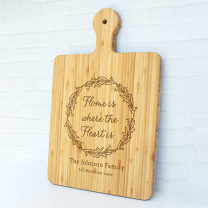 a cutting board with the words home is where the heart is