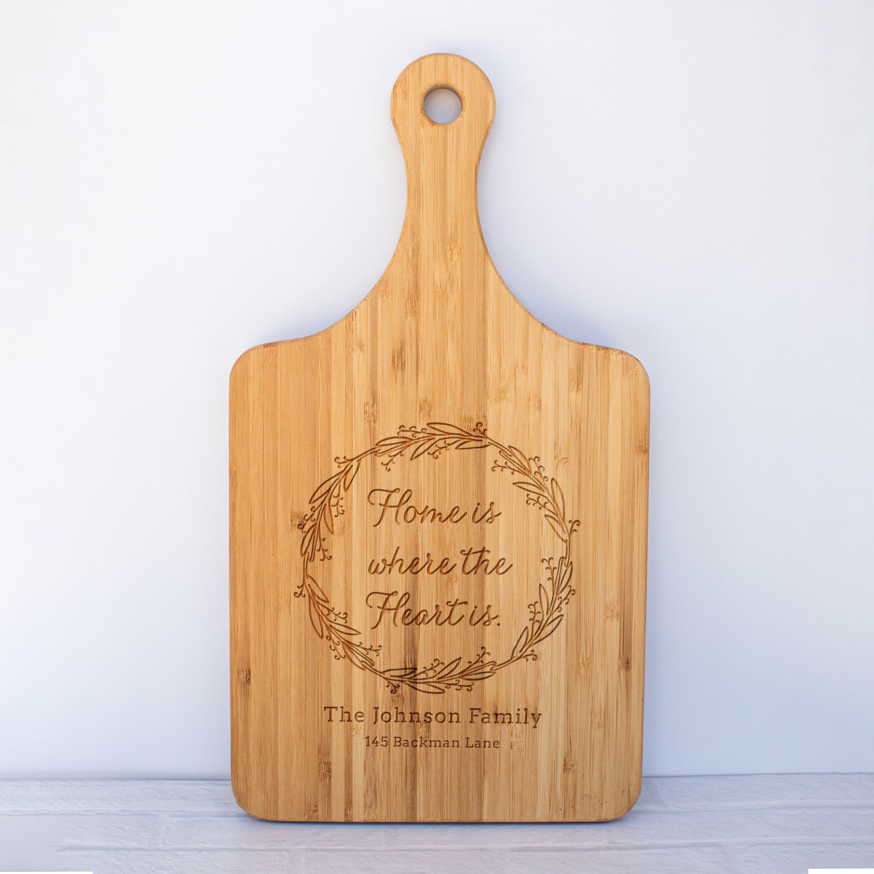 a cutting board with the words home is where the heart is