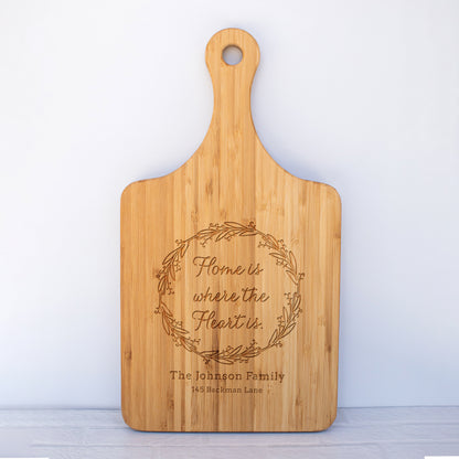 a cutting board with the words home is where the heart is