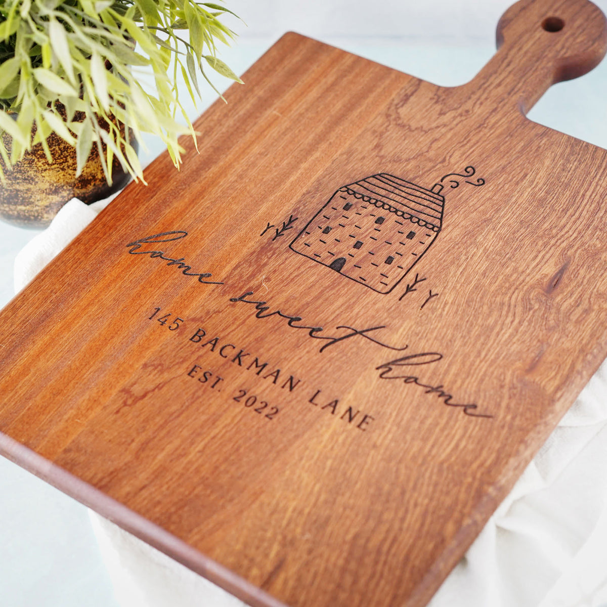 a wooden cutting board with a picture of a house on it