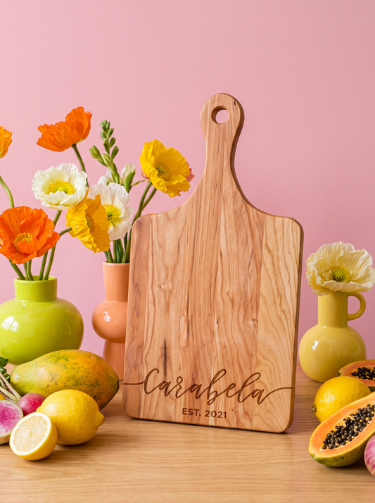 Flowing Script Family Name Cutting Board in a colorful floral setting