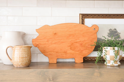 a wooden pig-shaped cutting board, a ceramic pitcher, and a potted plant on a shelf.
