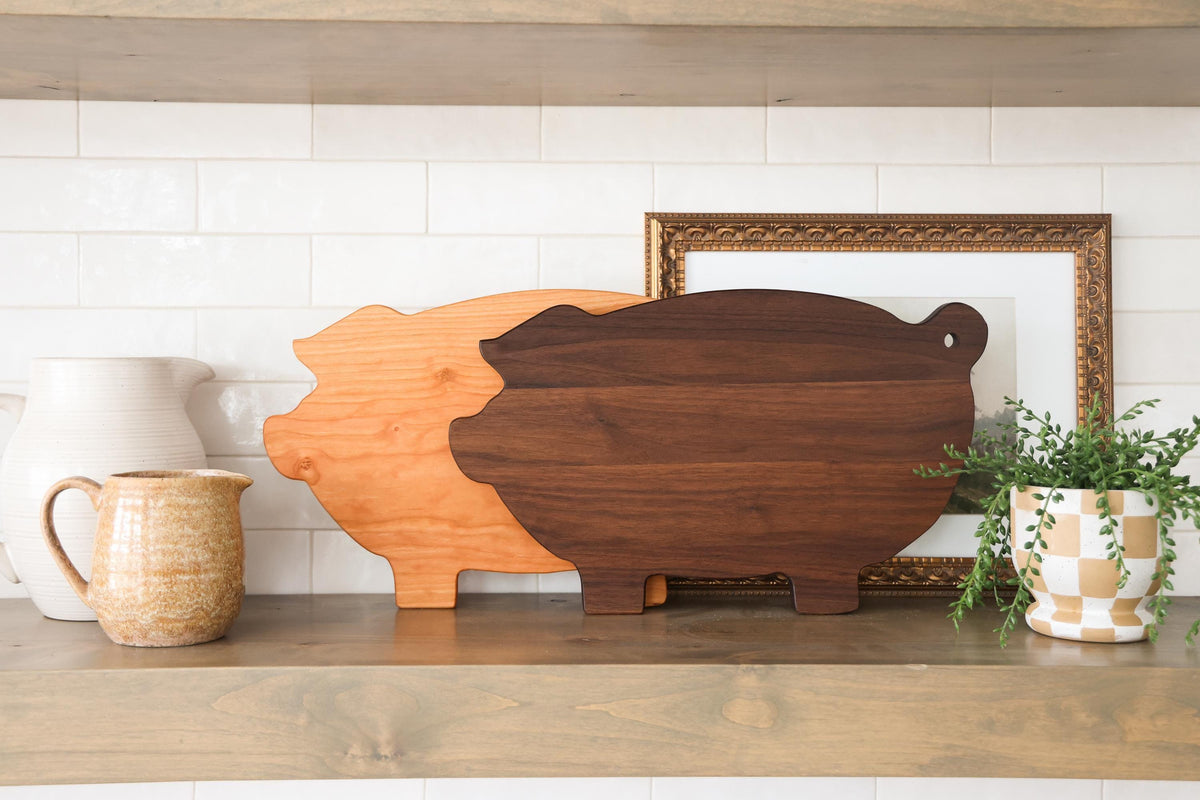 a wooden cutting board, a ceramic pitcher, a potted plant, and a framed picture on a shelf.