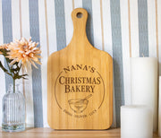 Holly Mixing Bowl edited mockup on a bamboo handled board, with Christmas Bakery lettering and grandkids’ names beside a flower vase and white candles.