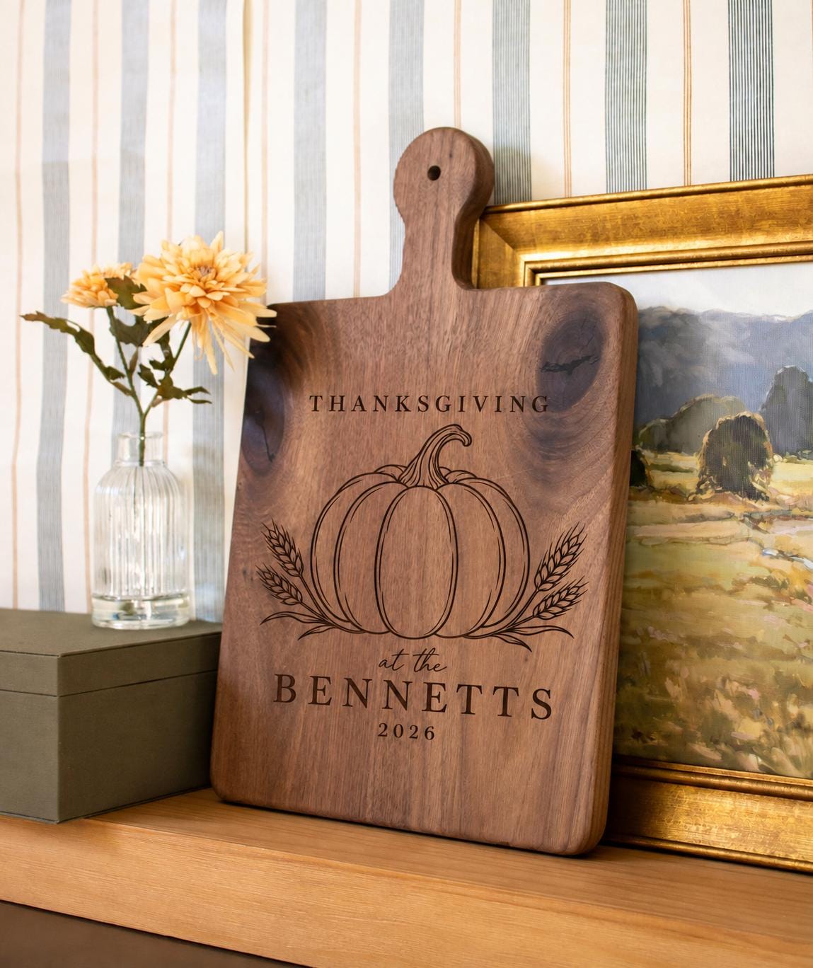 Pumpkin wheat Thanksgiving engraving mockup on a dark handled board beside yellow flowers and framed art, personalized BENNETTS 2026.