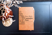 Edited mockup of a brown journal on a dark tabletop beside dried flowers, with a pen at its right edge; vintage book illustration and Eleanor Robert’s Commonplace Book cover.