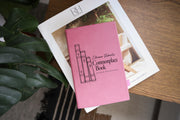 Edited mockup of a pink journal on an interiors book beside green leaves, with three illustrated book spines and the personalized Commonplace Book cover design.
