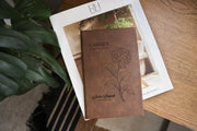 Brown Garden Hydrangea journal mockup on a book beside green leaves and a wood table. Cover shows a hydrangea, Garden Observations, Julia Bennett, and Field Notes.