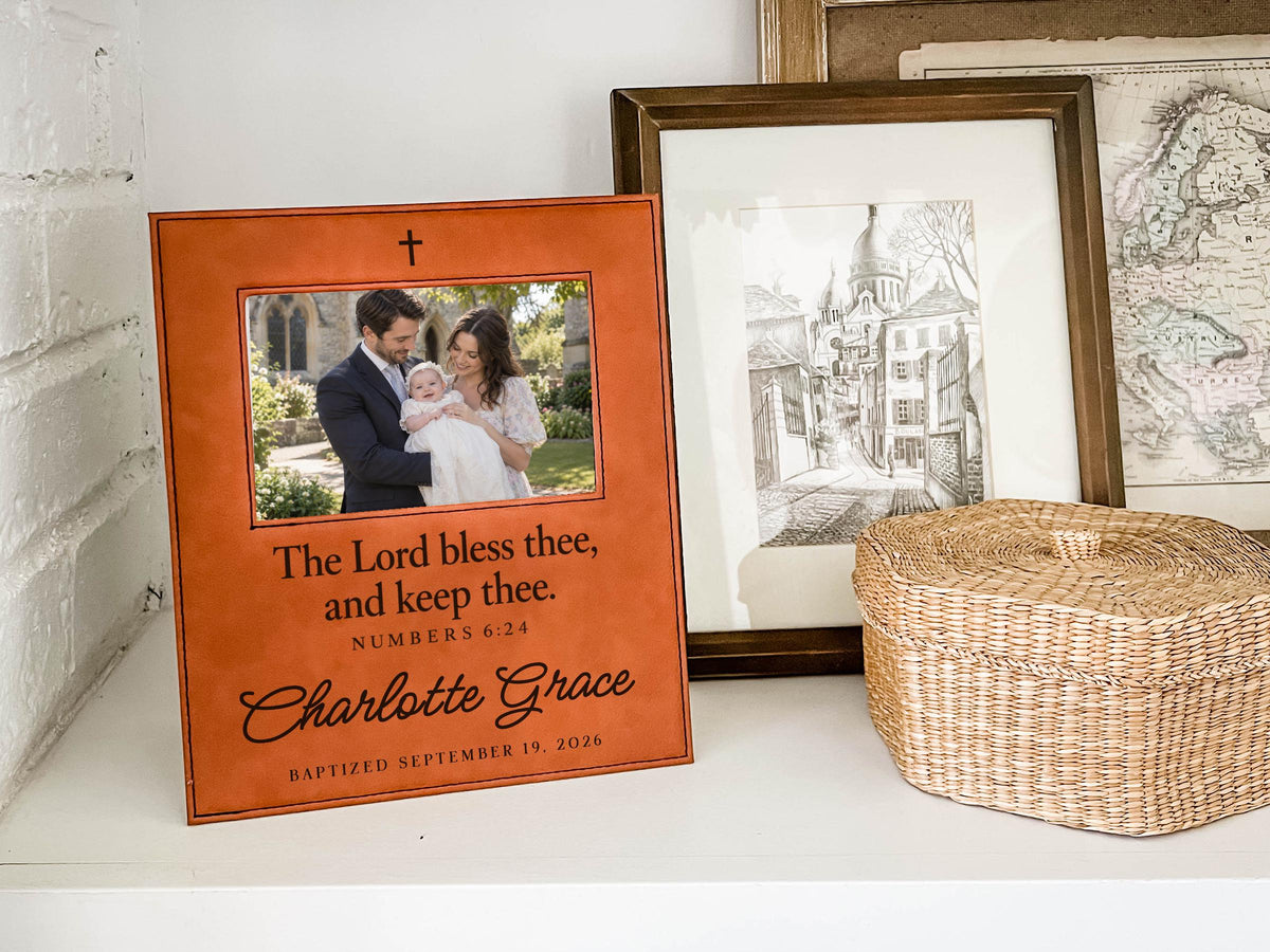 Edited mockup of the charlotte grace baptism frame beside a woven basket and framed drawings, with an illustrative family photograph, cross, blessing, sample name and date.