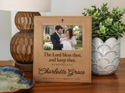 Edited mockup of the charlotte grace baptism frame beside a lamp and plant, with an illustrative family photograph, cross, Numbers 6:24 blessing, sample name and date.