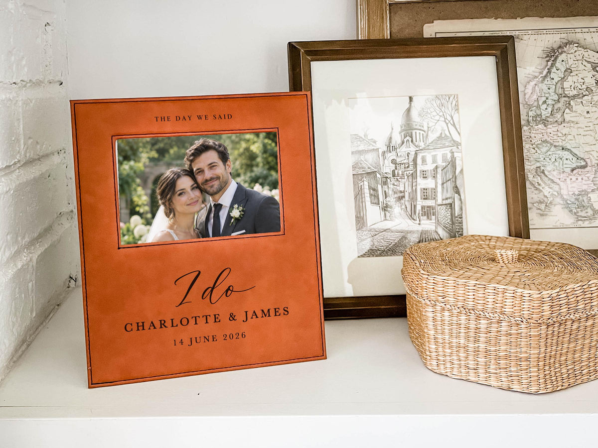 I Do wedding frame mockup on a shelf beside a woven basket and framed art, with an illustrative couple photo and the sample names Charlotte & James and date 14 June 2026.