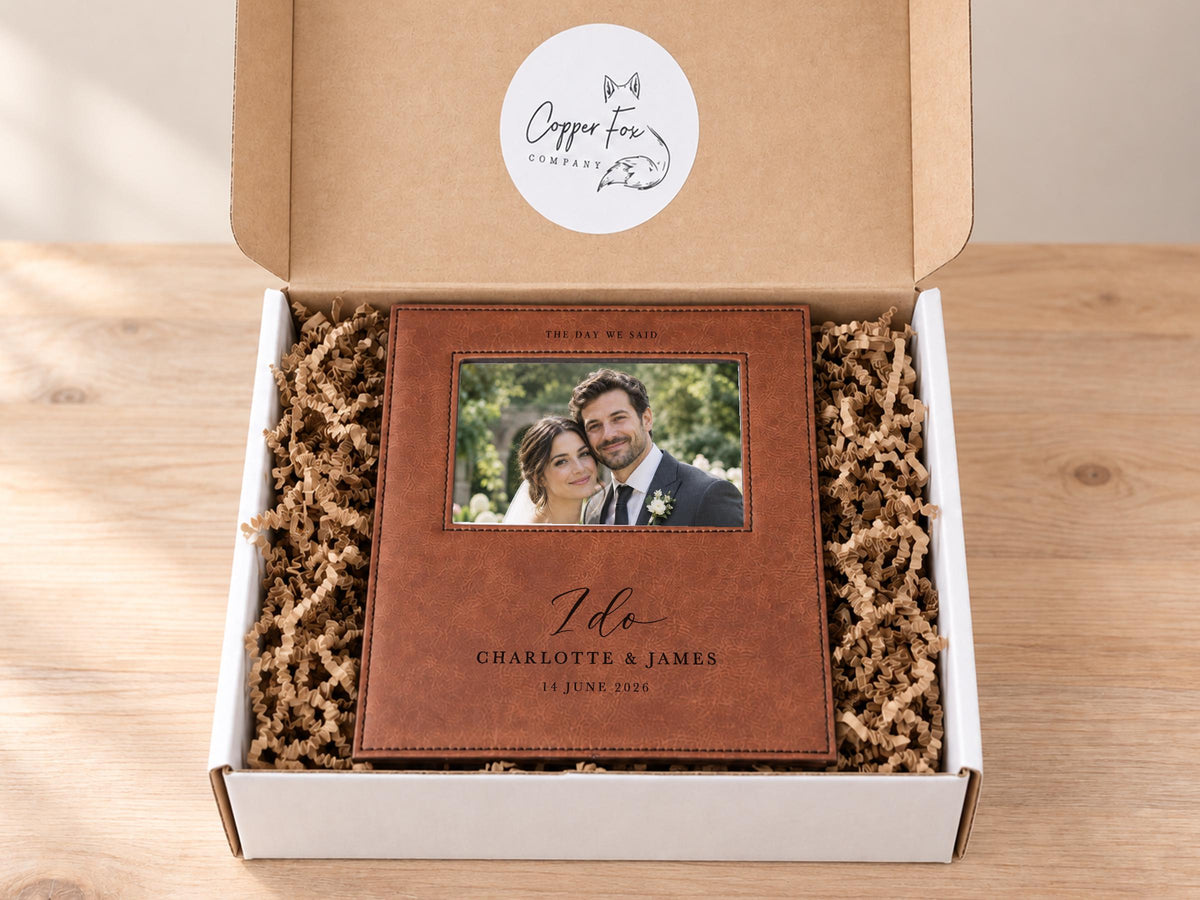 I Do wedding frame mockup inside an open Copper Fox gift box with crinkle paper, with an illustrative couple photo and the sample names Charlotte & James and date 14 June 2026.