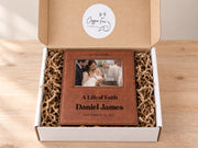 Edited mockup of the life of faith baptism frame in an open gift box with crinkle paper, sample Daniel James engraving and an illustrative baby baptism photo.