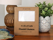 Edited mockup for Gift Options None: life of faith frame engraved with Daniel James and September 19, 2026, with an empty photo opening beside a lamp and plant.