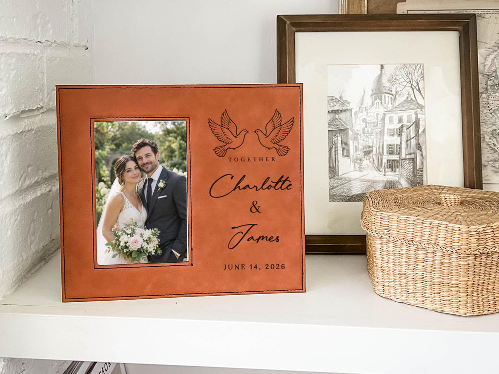 Edited mockup of a brown-toned Together frame on a shelf, with an illustrative wedding portrait at left and paired doves, Charlotte & James, and June 14, 2026 at right.