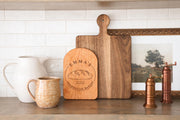 Edited mockup of a cherry arched board with the Sourdough Bakery emblem, displayed in front of a larger unengraved board; styling board is not included.