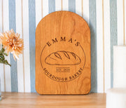 Edited mockup of a cherry arched cutting board with Emma’s Sourdough Bakery loaf emblem and EST. 2020.