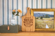 Generated engraving mockup of Emma’s Bread Kitchen with loaf, wheat and EST. 2020 on a bamboo cheese board.