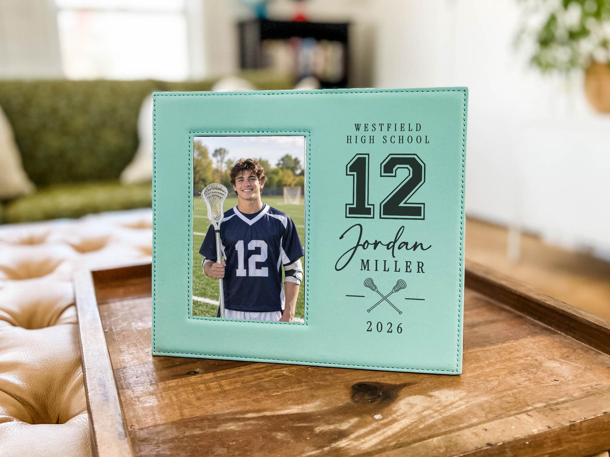 Teal Varsity Lacrosse frame mockup on a wooden tray, with a portrait on the left and school name, jersey number, player name, crossed lacrosse sticks and year on the right.