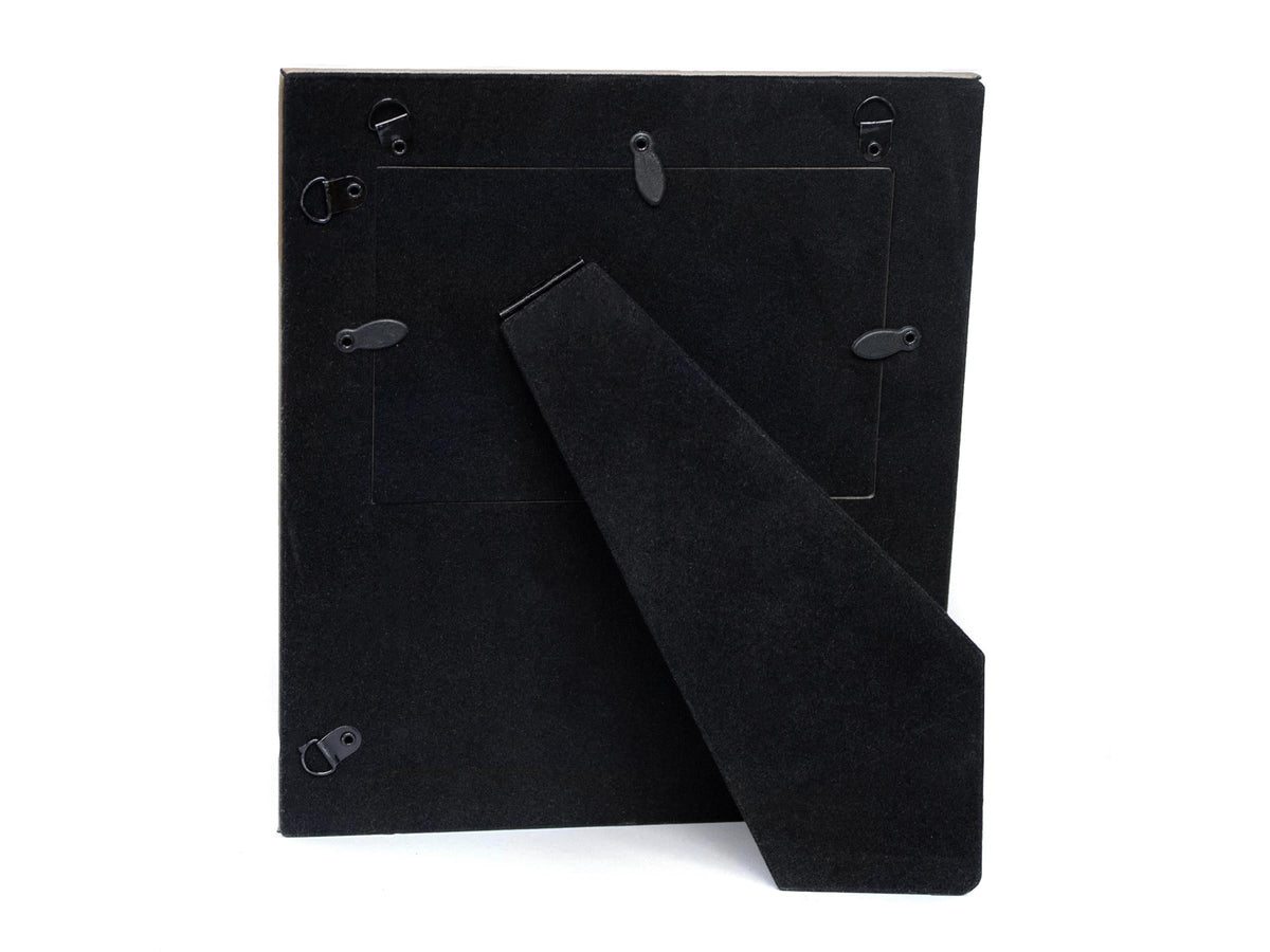 Rear view of a frame showing its black backing, folding stand, retaining tabs and hanging loops.