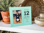 Edited teal Varsity Volleyball frame mockup beside a potted plant and woven tray, with an illustrative athlete portrait and the sample number 12, Jordan Miller, school and year.