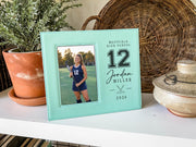 Teal Varsity Field Hockey frame beside a potted plant and woven basket, with an illustrative player portrait and sample school, name, number and year engraving.