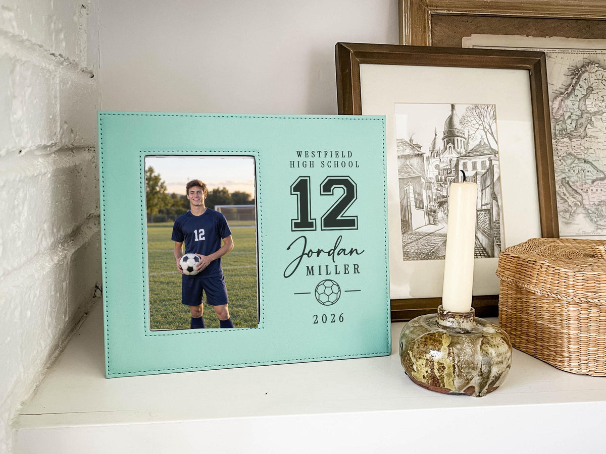 Edited Varsity Soccer frame mockup with an illustrative soccer player portrait on the left and sample Westfield High School, number 12, Jordan Miller and 2026 engraving on the right.