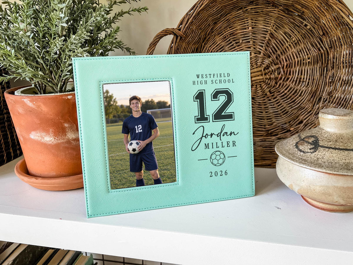 Edited Varsity Soccer frame mockup with an illustrative soccer player portrait on the left and sample Westfield High School, number 12, Jordan Miller and 2026 engraving on the right.