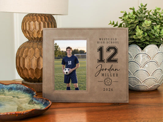 Edited Varsity Soccer frame mockup with an illustrative soccer player portrait on the left and sample Westfield High School, number 12, Jordan Miller and 2026 engraving on the right.