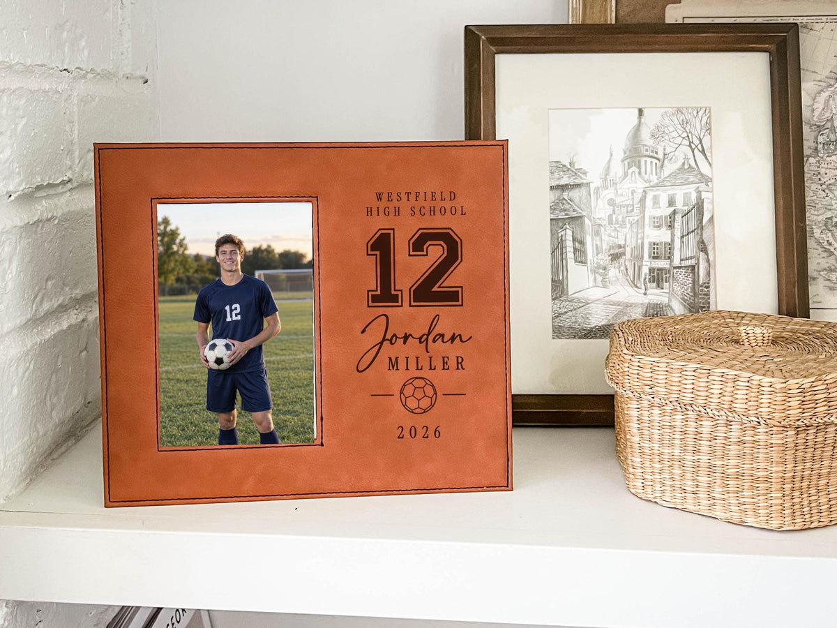 Edited Varsity Soccer frame mockup with an illustrative soccer player portrait on the left and sample Westfield High School, number 12, Jordan Miller and 2026 engraving on the right.