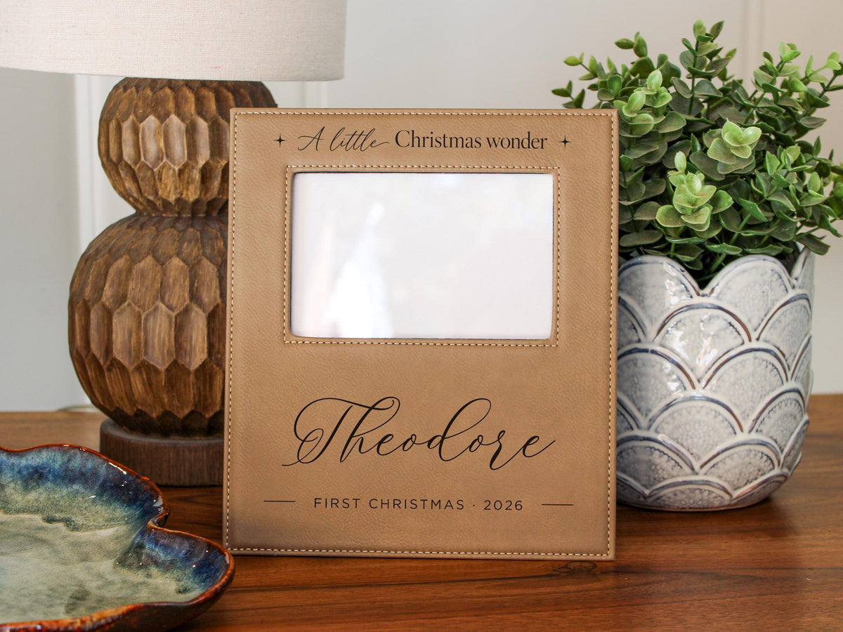 Edited mockup for Gift Options None: Christmas Wonder frame engraved with Theodore and First Christmas 2026, with the original empty photo opening and no inserted photo.