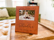 Edited mockup of Christmas Wonder frame engraved with Theodore and First Christmas 2026 around an illustrative baby photo, standing on a tray.