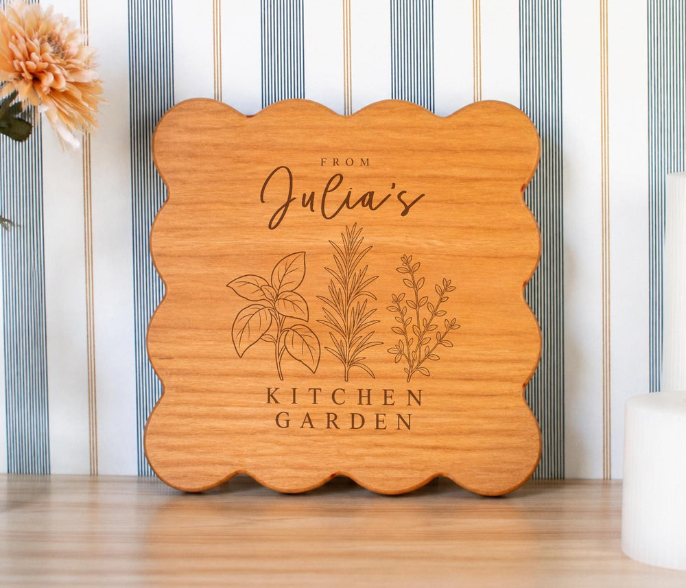 Kitchen Garden Trio personalized cutting board with three botanical herb sprigs and sample name wording; edited mockup.